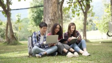 Birkaç nesil boyunca parlak genç öğrenciler parkta sınavlar için hazırlanıyorlar. Birlikte kitap okuyun ve dizüstü bilgisayar eğitimi kavramını kullanın. Akıllı öğrenci öğretmeniyle açık havada mutlu bir ders alıyor..