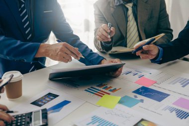 Bir grup iş adamı bir pazarlama planının verilerini analiz etmek için toplanıyor. Ofis çalışanları, proje planlama belgeleriyle birlikte konferans masasında bir takım toplantısında çalışıyorlar. Yakın plan resimler.