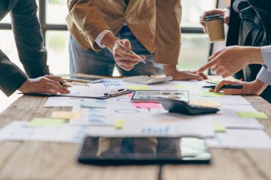 Bir grup iş adamı bir pazarlama planının verilerini analiz etmek için toplanıyor. Ofis çalışanları, proje planlama belgeleriyle birlikte konferans masasında bir takım toplantısında çalışıyorlar. Yakın plan resimler.