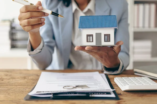 A salesperson or broker offers a special promotion and free insurance to a customer who purchases a real estate sample home is reviewing documents before the customer agrees to sign a contract to purchase a home in the project.