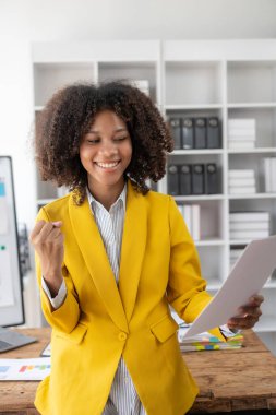 Evde mali belgelerle çalışan genç siyahi bir kadının, İnternet 'te vergi makbuzunu ödemeden önce hesap makinesi kullanması gerekiyor. Tasarruf için bütçenizi planlayın. dikey resim