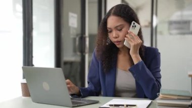 Laptop akıllı telefonu kullanarak gülümseyen genç Afrikalı kadın. Masadaki matematik, vergi hesapları, raporlar, muhasebe, istatistik ve analitik araştırma kavramları, finans 4 bin.