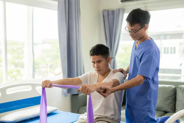 Physiotherapy doctor treating patient whose arm is recovering, doing physical therapy to stretch muscles in clinic