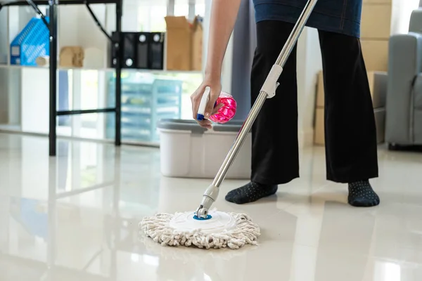 Maid wearing an apron provides cleaning services at home. Close-up of a young woman cleaning a new house or apartment while moving in copy space