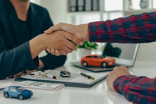 Man buys car and shakes hands with business salesman, closing car sales agreement, gesture and concept of giving keys to new owner and shaking hands at car show Close-up pictures