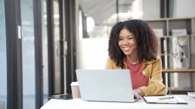 Afrikalı kadın girişimci belgeleri kontrol ediyor ve e-posta yolluyor, profesyonel iş adamı bilgisayar üzerinde sörf yapıyor. Arkaplan olarak renkli ışıklarla programa göre fazla mesai yapma kavramı var.