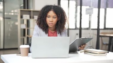 Afrikalı kadın girişimci belgeleri kontrol ediyor ve e-posta yolluyor, profesyonel iş adamı bilgisayar üzerinde sörf yapıyor. Arkaplan olarak renkli ışıklarla programa göre fazla mesai yapma kavramı var.