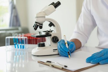 Laboratuvar konsepti: Laboratuvarda kimyasallara yakın çekim yapan bir biyokimyager, laboratuvarda kontrollü bir ortamda deneyler yapıyor. Doktor eldiven giymiş, elinde test tüpü tutuyor.
