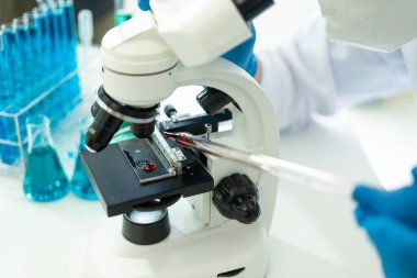 Laboratuvar konsepti: Laboratuvarda kimyasallara yakın çekim yapan bir biyokimyager, laboratuvarda kontrollü bir ortamda deneyler yapıyor. Doktor eldiven giymiş, elinde test tüpü tutuyor.