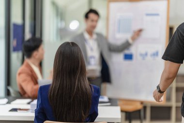 Takım elbiseli Asyalı başarılı iş adamlarından oluşan bir ekip beyin fırtınası, hesaplama, analiz ve şirket büyüme hedefleri ve brüt kâr marjlarını tartışmak için konferans odasında çalışıyor..