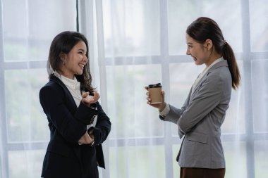 İki Asyalı kadın muhasebeci iş ofisindeki finansal bilgileri özetlemek için takım toplantısı yapıyorlar. Yaratıcı kadın yönetici tableti kullanıyor ve gülümsüyor.