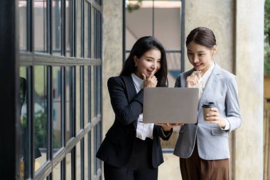 İki Asyalı kadın muhasebeci iş ofisindeki finansal bilgileri özetlemek için takım toplantısı yapıyorlar. Yaratıcı kadın yönetici tableti kullanıyor ve gülümsüyor.