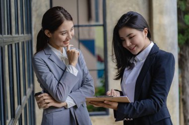 İki Asyalı kadın muhasebeci iş ofisindeki finansal bilgileri özetlemek için takım toplantısı yapıyorlar. Yaratıcı kadın yönetici tableti kullanıyor ve gülümsüyor.