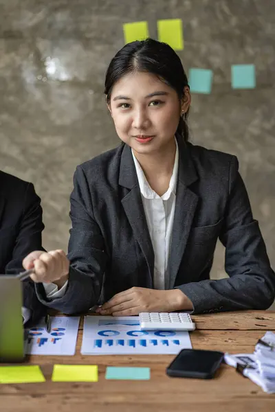 Young professional Asian accountant or financial analyst presents a financial report during a financial business sales data meeting with her colleagues in the office.