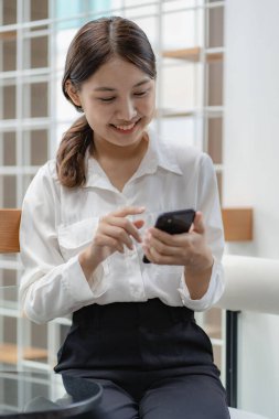 Elinde akıllı telefon kullanan sevimli Asyalı kadın teknoloji konsepti ve internette sörf yapan ve internetten alışveriş yapan insanlar. Dikey resim.