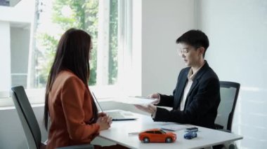 Araba satmak ya da kiralamak için otomotiv işi fikirleri. Müşteri ve araba satıcısı anlaşma yapar ve sözleşmeyi imzalar. Araba satış bürosundaki belge sözleşmesi 4K