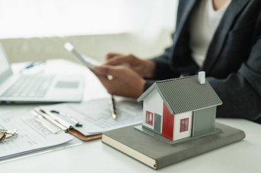 Bir emlakçı müşterileri tanıtmak için küçük bir ev modeli tutuyor. Model ev projesi ve müşterilere anahtar verilmesi konut kredisi ve sigorta sözleşmesi için yeni alıcılar onaylanır.