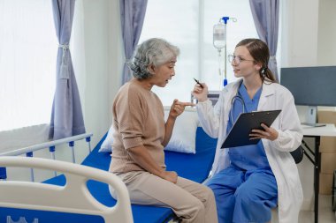 Kadın bir doktor test sonuçlarına bakarken yaşlı bir kadın hastayla konuşur. Bir hasta, kadın bir doktora tedavi ve sağlık tavsiyesi hakkında danışmaktadır..