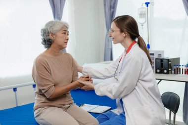 Kadın bir doktor test sonuçlarına bakarken yaşlı bir kadın hastayla konuşur. Bir hasta, kadın bir doktora tedavi ve sağlık tavsiyesi hakkında danışmaktadır..