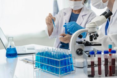 İki güzel genç bilim adamı ve yaşlı kadın test tüpleriyle bir laboratuvarda çalışıyorlar ve sağlık sektöründe mavi kimyasallar üzerine araştırma yapıyorlar..