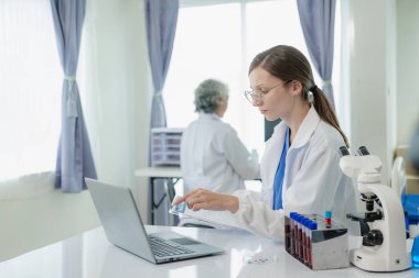 İki güzel genç bilim adamı ve yaşlı kadın test tüpleriyle bir laboratuvarda çalışıyorlar ve sağlık sektöründe mavi kimyasallar üzerine araştırma yapıyorlar..