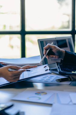 İki numaralı iş adamı muhasebe belgeleri üzerinde çalışıyor ve ekip sunum yapmak ve muhasebe belgeleriyle ilgili sorunları çözmek için birlikte çalışıyor. Dikey resmi kapat