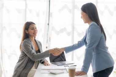 İki kendine güvenen iş kadını başarı toplantısı, temas, selamlama ve ortaklık çalışma süreci sırasında el sıkışıyor ve proje fikir belgelerinin sunumunu tartışıyorlar. Pazarlama planlarını analiz et