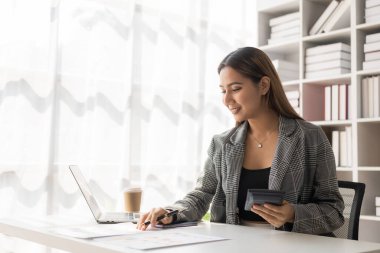 İç işlerinde çalışan Asyalı iş kadını mali belgeleri, hesap makinesini, telefonu, bilgisayarı, masadaki finansal rapor kavramını analiz ediyor. iş planı yatırımı