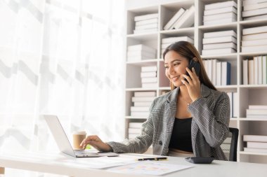 İç işlerinde çalışan Asyalı iş kadını mali belgeleri, hesap makinesini, telefonu, bilgisayarı, masadaki finansal rapor kavramını analiz ediyor. iş planı yatırımı