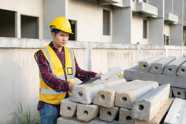 Young man engineer or construction supervisor inspecting work on project, architect wearing helmet and vest doing inspection and inspection. Quality of work done