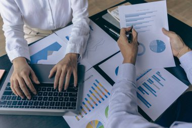 İş adamlarıyla takım çalışması maliyet grafiklerini bir iş konferansı odasında analiz eder ve ofis çalışanları proje planlama belgeleriyle bir konferans masasında çalışır, yakın plan fotoğrafçılık.