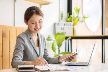 Ofiste dizüstü bilgisayarla çalışan neşeli Asyalı kadın, resmi takım elbiseli mutlu, ofiste çalışan, gülümseyen kadın ofis çalışanı, finansal muhasebe kavramı