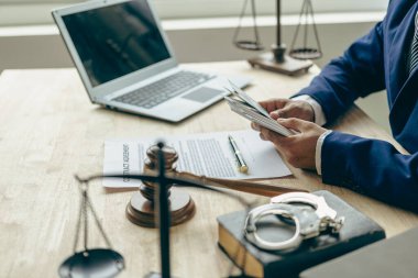 Avukat para ve adalet kavramını elinde tutuyor. Yasal danışman elinde çekiçli bir dolar tutuyor ve adaletsizlik tanrıçası masada. Yolsuzluk ve zimmete para geçirme kavramı