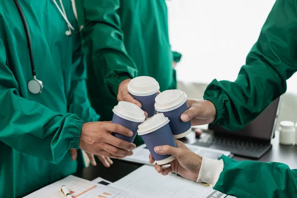 Medical team holding coffee cups, clinking coffee cups, celebrating success, team meeting to brainstorm treatment ideas, close-up photo