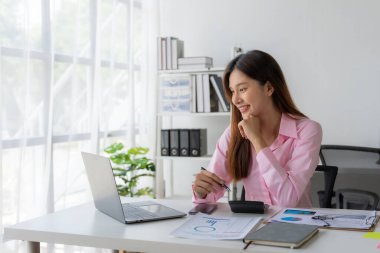 Yıllık özet raporu, masadaki dizüstü bilgisayar ve kağıt, çevrimiçi çalışan Asyalı kadın ve dizüstü bilgisayarla finansal veri planlaması ve heyecanlı ve mutlu yüzle başarılı olması