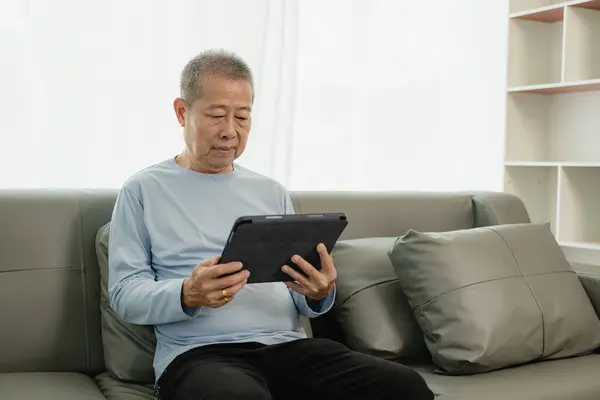 Senior Uomo Asiatico Sul Divano Utilizza Tablet Navigare Internet Leggere — Foto Stock