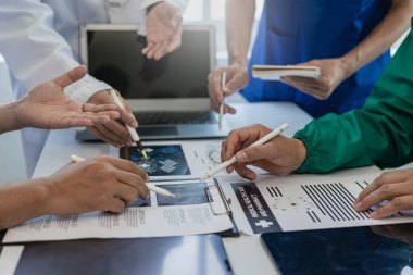 Ofis ekipleri için beyin fırtınası ve planlama üzerine toplantılar ve dizüstü bilgisayarlar. Masalardaki doktorlar, hemşireler ve bilgisayarlar işbirliğinin çeşitliliğini gösteriyor. Yakın plan resimler.