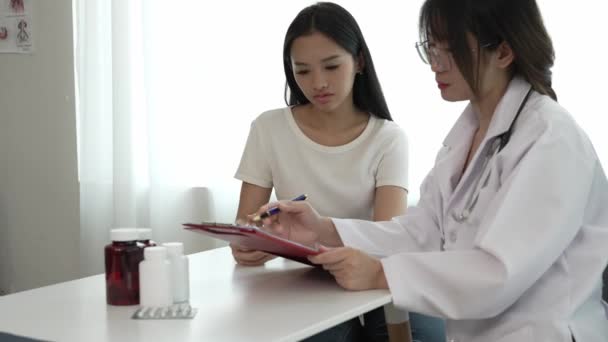 Azjatycki Lekarz Białym Mundurze Medycznym Omawia Wyniki Lub Objawy Pacjentką — Wideo stockowe