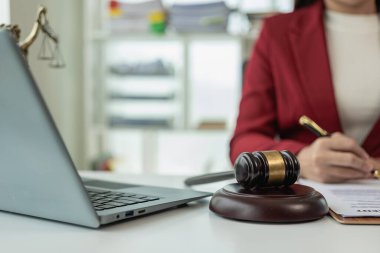 Ofiste ya da mahkemede çalışan Asyalı kadın avukat. Masasında çekiç ve adalet yastığı var. Yeni emlak yasalarıyla ilgili online hukuki tavsiyeler var. Hukuk, hukuk, danışmanlık, adalet.