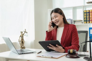 Ofiste ya da mahkemede çalışan Asyalı kadın avukat. Masasında çekiç ve adalet yastığı var. Yeni emlak yasalarıyla ilgili online hukuki tavsiyeler var. Hukuk, hukuk, danışmanlık, adalet.