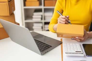 Kadın çevrimiçi dükkan küçük işletme sahibi satıcı paketi nakliye kutusunun arkasına koyar. KOBİ 'nin e-ticaret dağıtım hizmeti kavramı için paketler hazırlanıyor. Yakın plan..
