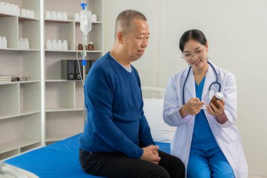 Yetkili bir hemşire, hastane bölümündeki bir odada uyumak için kıdemli bir adama bakıyor. Asyalı kadın doktor yatakta erkek hastayla ağrı ve semptomları, hayat sigortası konsepti hakkında konuşuyor.