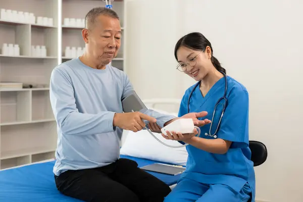 一名负责照顾老年人的护士在医院病房的一个房间里睡觉 亚洲女医生在床上与男病人谈论他的疼痛和症状 人寿保险的概念 — 图库照片