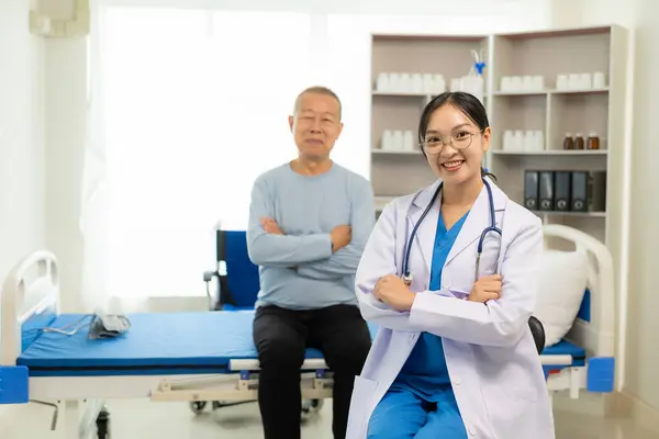 担当の看護師は 高齢者の世話をして 病院の部門の部屋で寝る アジアの女性医師は 彼の痛みと症状 生命保険の概念についてベッドで男性患者と話します — ストック写真