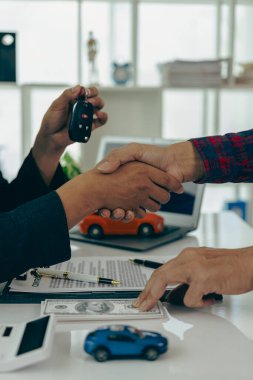 Araba işi, araba satışları, anlaşmalar, el kol hareketleri ve yakın çekim satıcılarının yeni sahibine anahtarlarını vermesi ve masada el sıkışması, yakın çekim fotoğrafı.