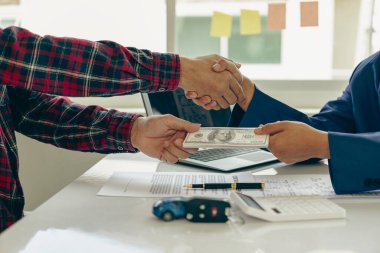 Araba işi, araba satışları, anlaşmalar, el kol hareketleri ve yakın çekim satıcılarının yeni sahibine anahtarlarını vermesi ve masada el sıkışması, yakın çekim fotoğrafı.