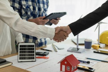 İnşaat ekibinin el sıkışması ile birlikte masa ve ev tasarımı tasarımı tasarımı sarı başlık İnşaat sahası ortağı ve müteahhit ofis merkezinde yeni proje sözleşmesi planı başlat