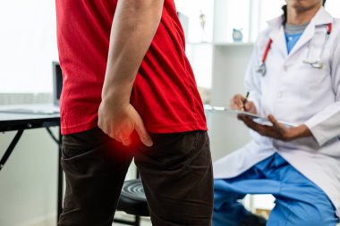 Man consulting doctor about hemorrhoids squeezes his butt treatment concept. Man touches her buttocks because of abdominal pain and hemorrhoids. health care concept
