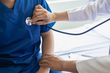 Stetoskop kullanan Kalp ve Akciğer Sağlığı Kontrol Kliniği erkek doktoru. Sağlık muayenehanesinde oturan hastaların solunum seslerini dinle. Kalp ve sağlık danışmanı tarafından takip edilen insanlar