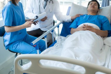 Yatakta Asya kökenli bir erkek hasta, hastanedeki, sağlık, sağlık ve sigorta konularında doktordan iyi haberler alıyor..